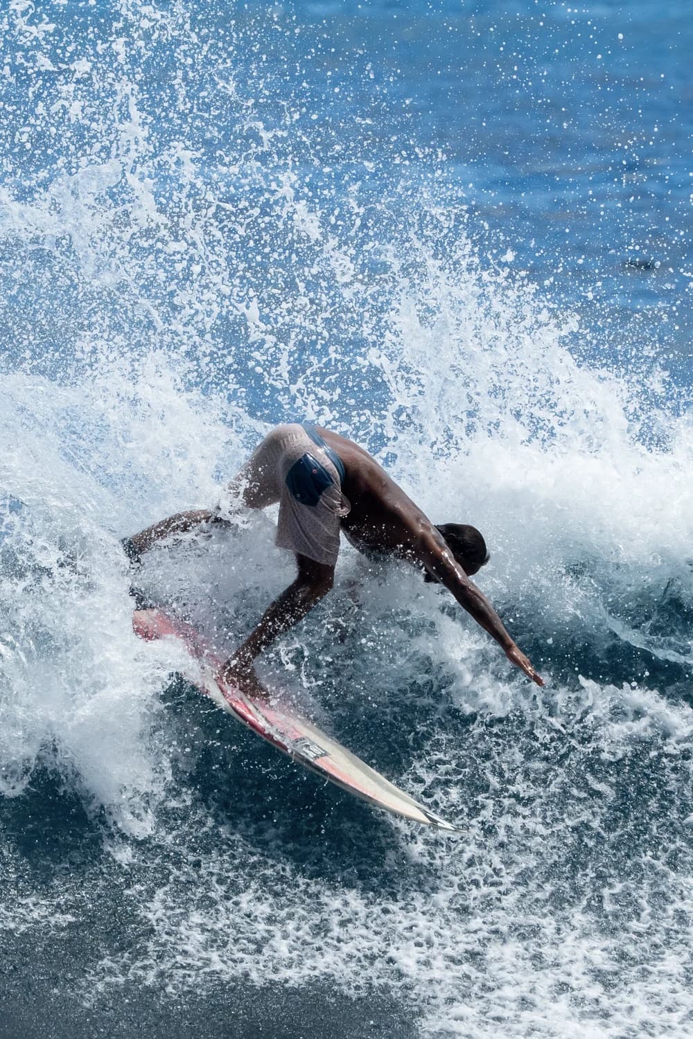 Surfer driving through a top turn with spray at Siargao