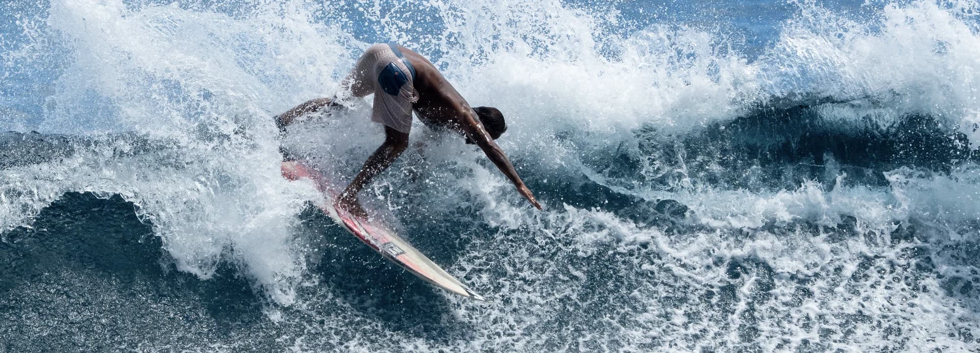 Surfer driving through a top turn with spray at Siargao
