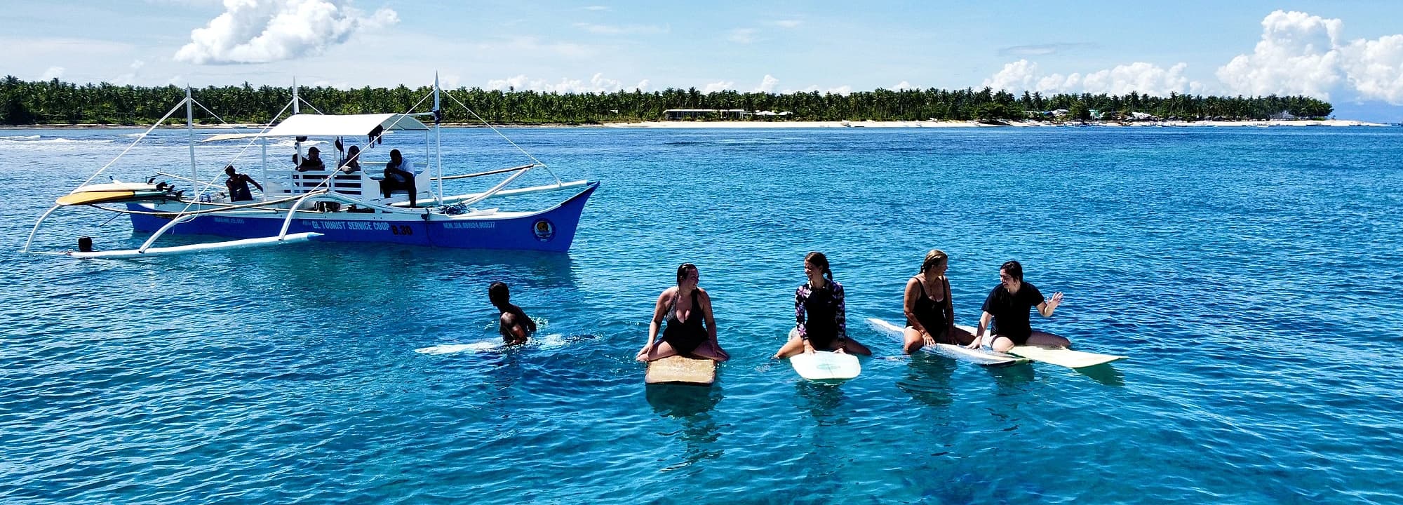 Group surf lesson on boards in the turquoise water off Siargao
